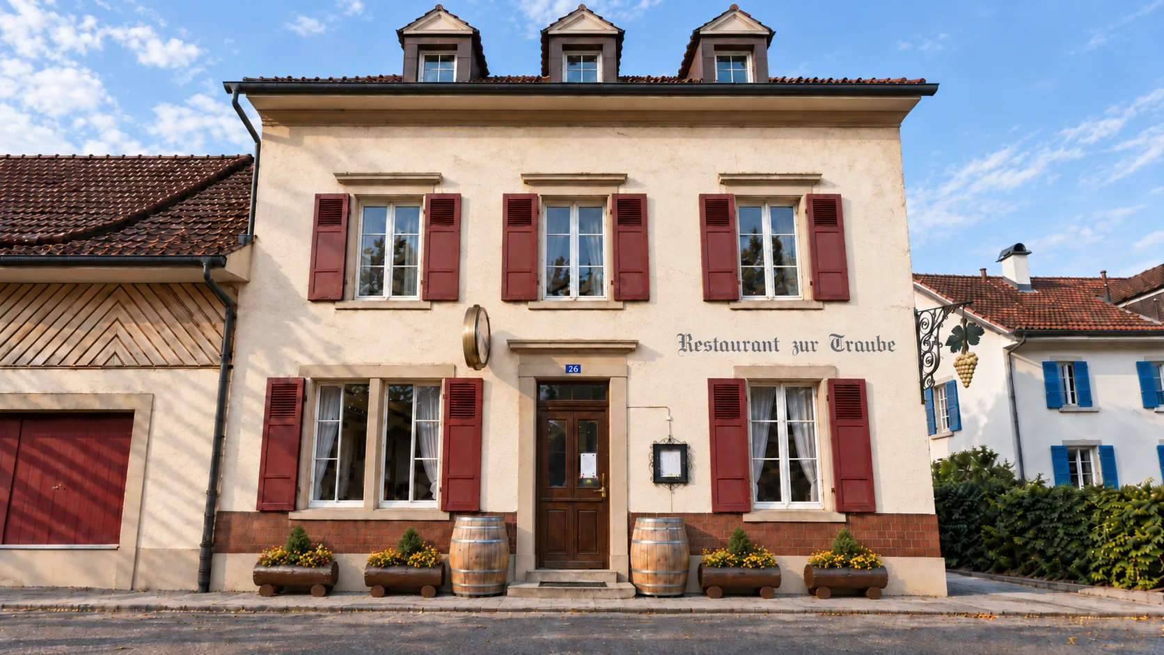 Fassade des Restaurants Zur Traube an der Therwilerstrasse 26 mit weinroten Fensterläden und Weinfässern
