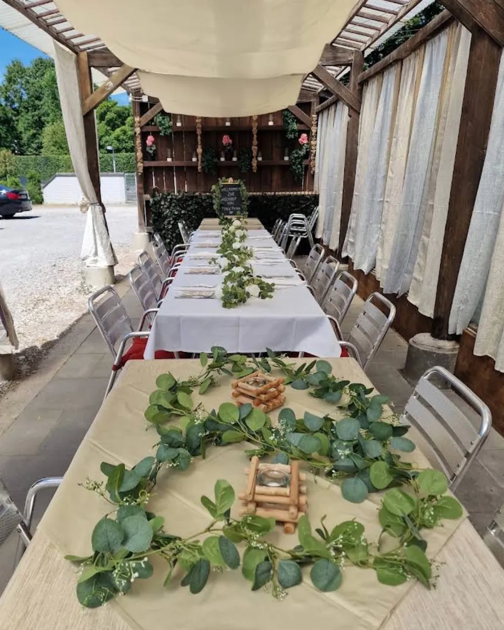 Festlich gedeckte Tafel auf der gedeckten Terrasse mit Eukalyptus-Girlanden